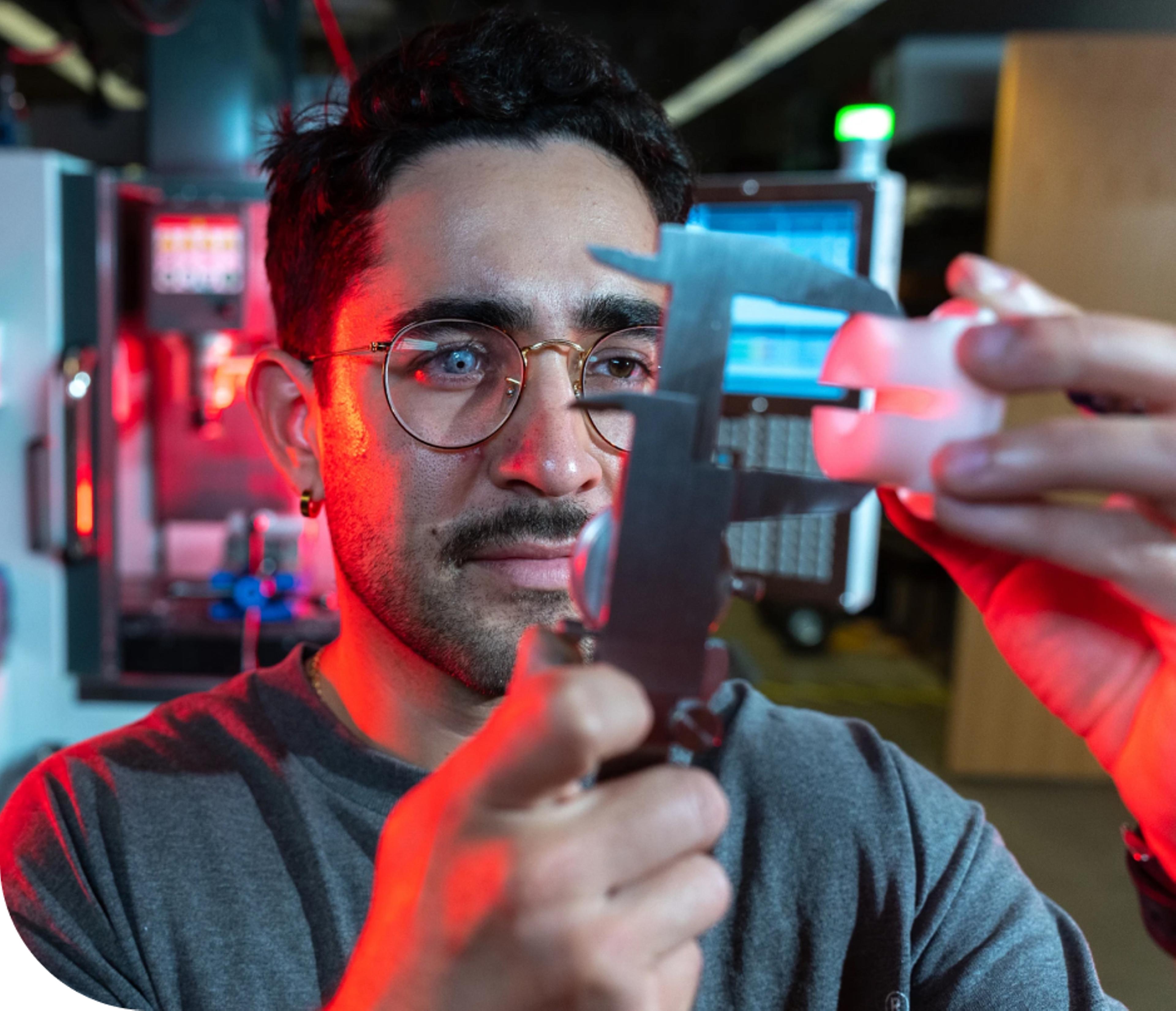 A focusedDU student using precision measurement tools in a laboratory setting, with red and blue lighting highlighting the equipment.